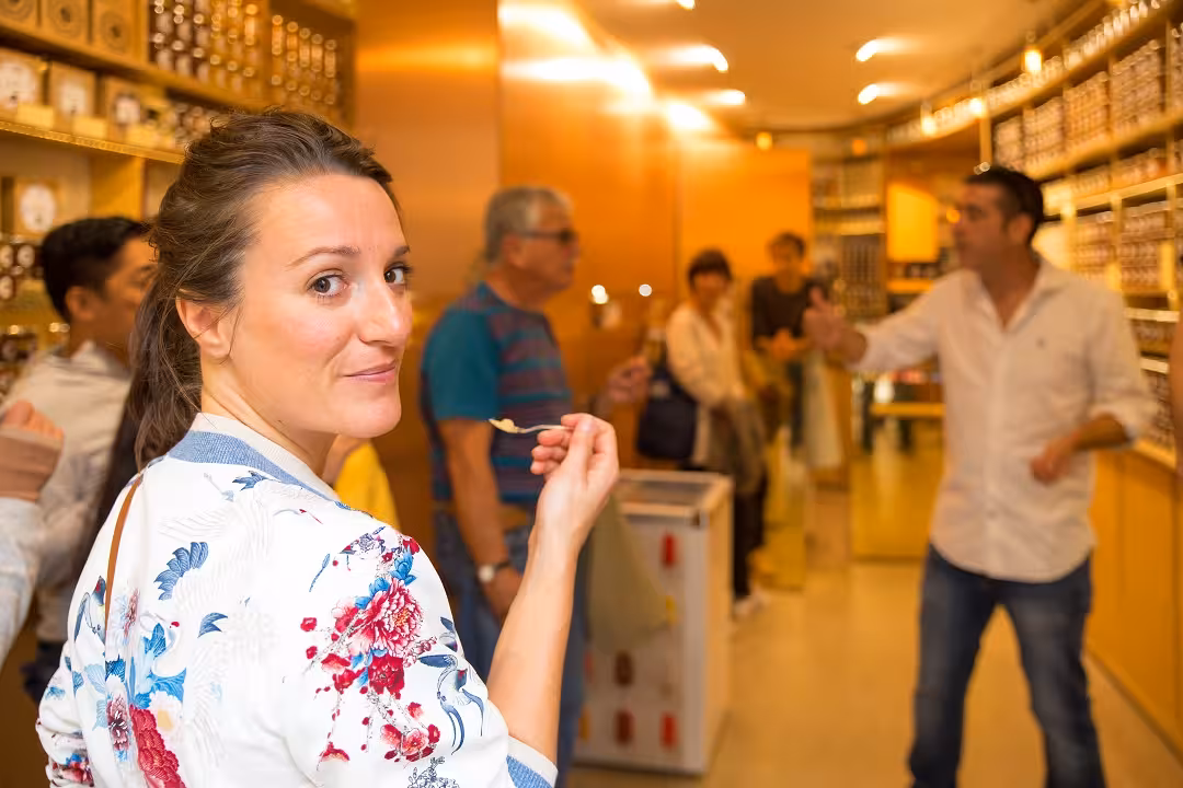 Woman savoring flavors during Marais District food tour with wine and cheese tasting in cozy shop setting.