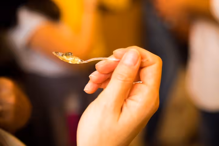 Close-up of a hand holding a spoon with gourmet food during the Marais private food tour in Paris.