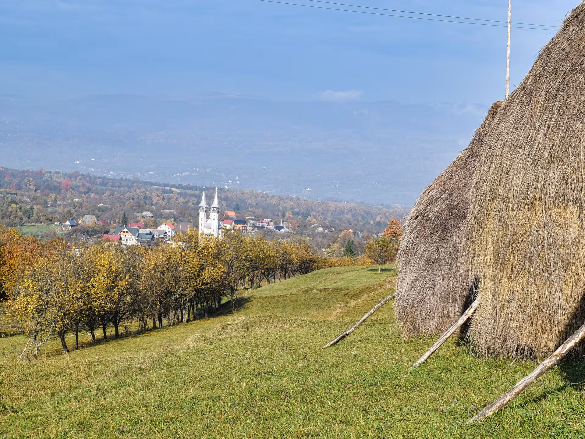 Scenic Maramures rural village landscape with church spires and traditional haystack during autumn guided tour