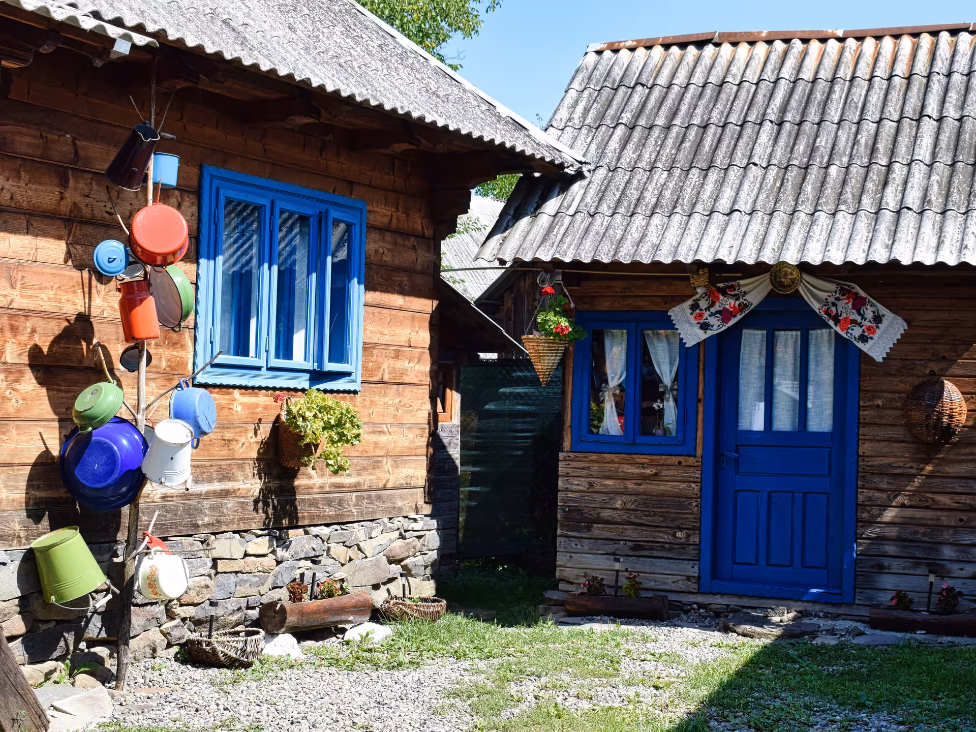 Traditional wooden houses with blue doors and windows in Maramures village, decorated with colorful pots and folk textiles