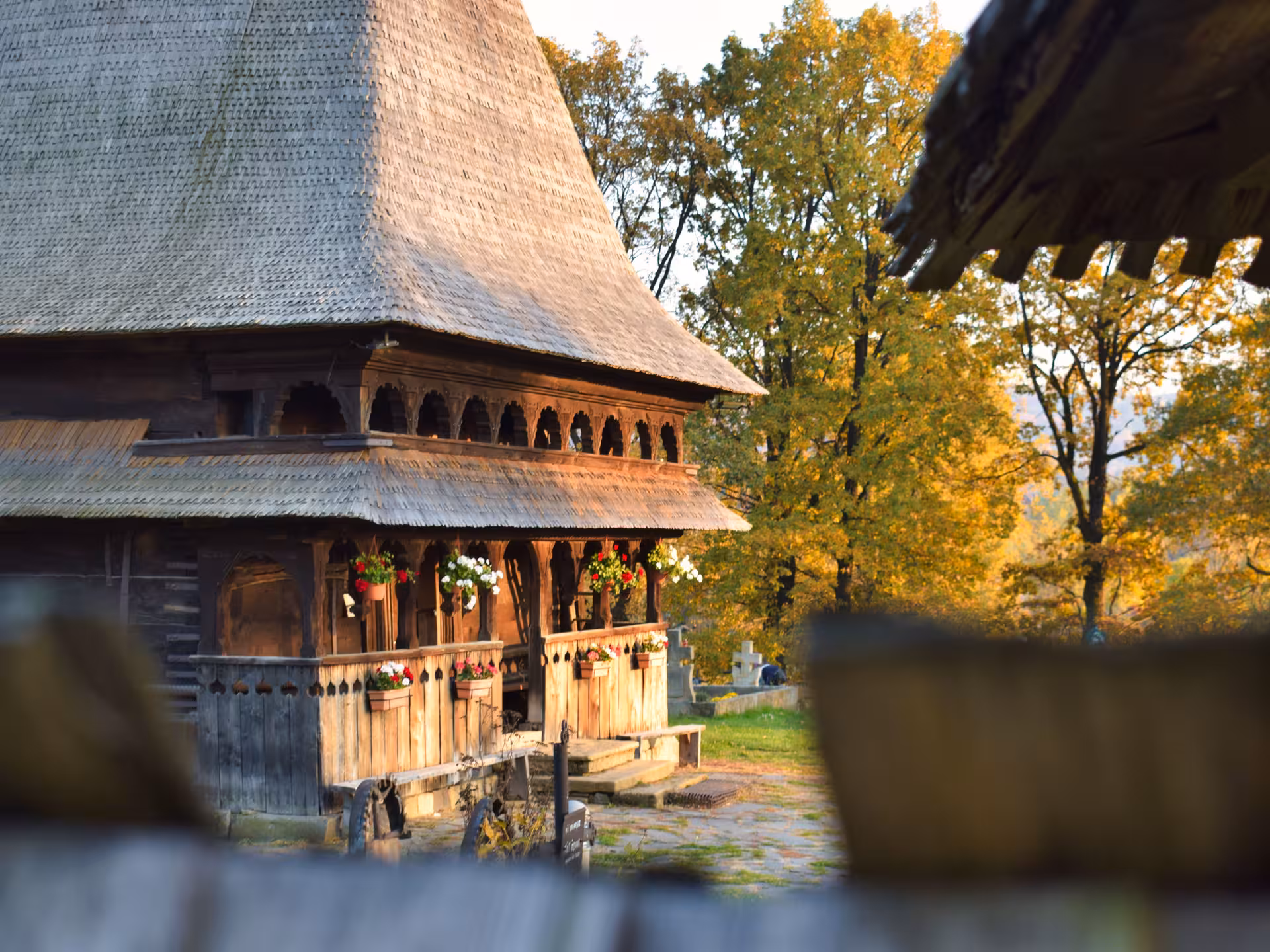 Historic wooden church with carved porch and flower pots in Maramures Romania on a 3-day guided tour from Cluj