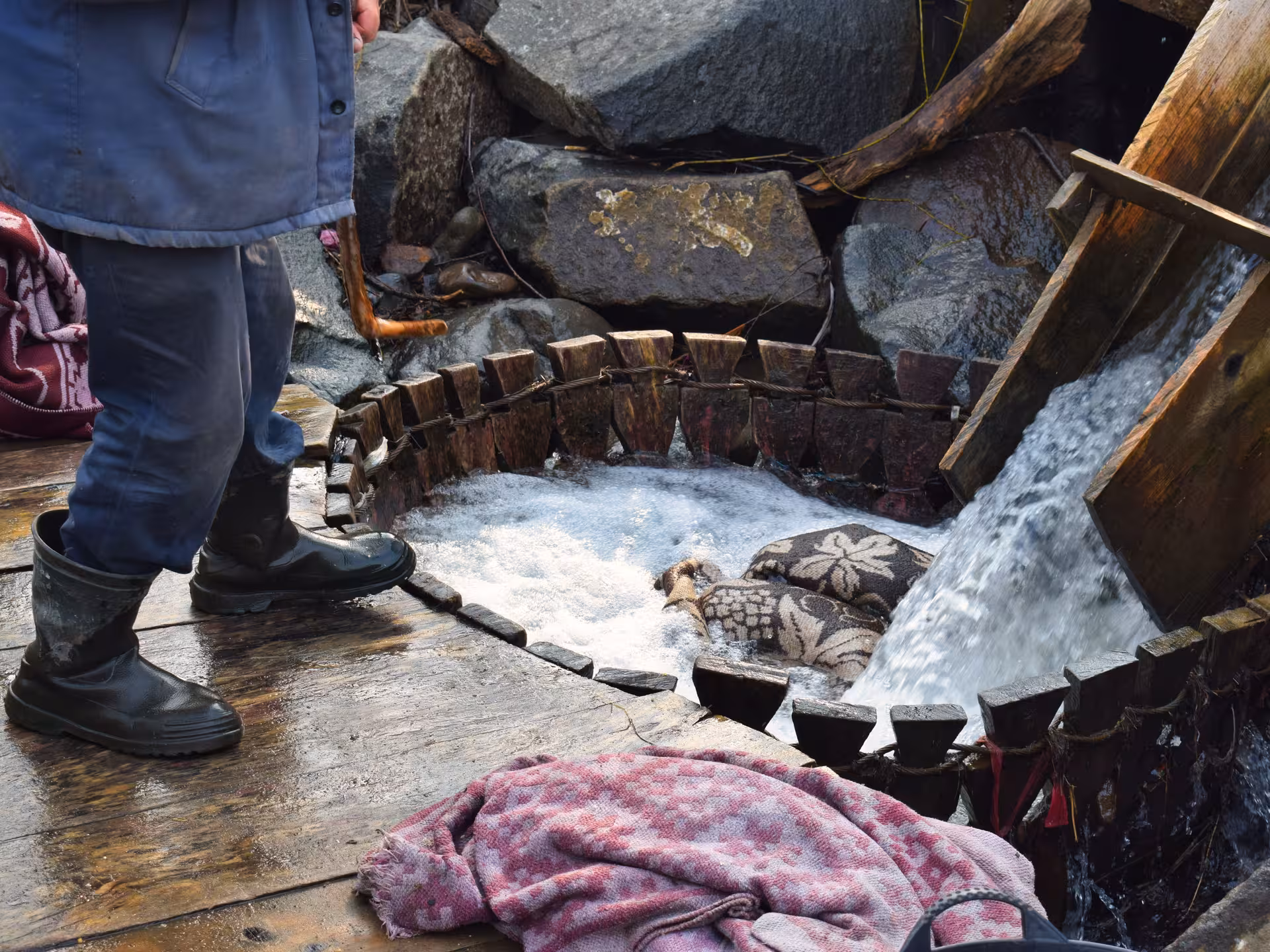 Artisan demonstrating traditional wool felting at a wooden water mill during a Maramures guided tour from Cluj