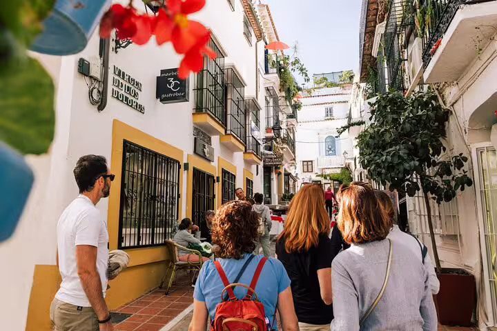 Tourists exploring the narrow, picturesque streets of Marbella Old Town lined with colorful flowers and quaint buildings.