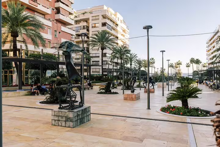 Charming plaza with modern sculptures and palm trees in Marbella Old Town, ideal for a scenic walking tour.