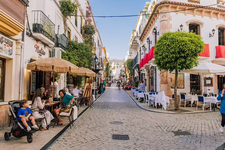 Charming street in Marbella Old Town with outdoor cafes and historic architecture on a sunny day.