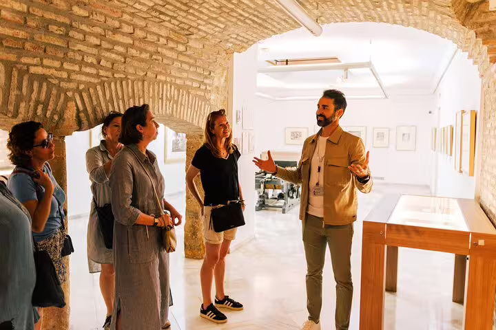 Tour group listens intently to a guide in a historic brick archway during the Marbella Old Town walking tour.