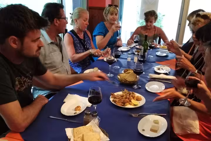 Tourists savoring traditional tapas and wine at a vibrant Marbella dining spot, highlighting a cultural culinary experience.