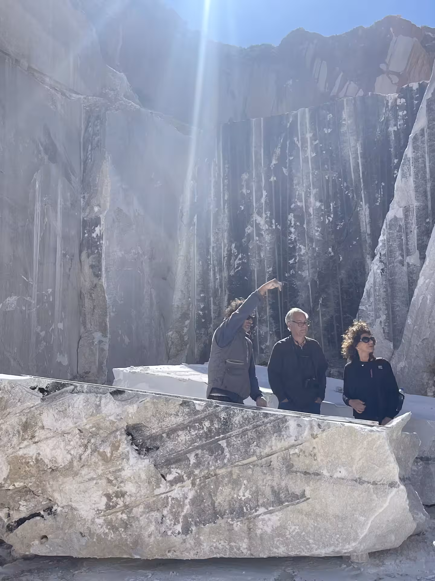 Visitors in a marble quarry on the Marble World tour, with towering stone walls and sunlit rock blocks