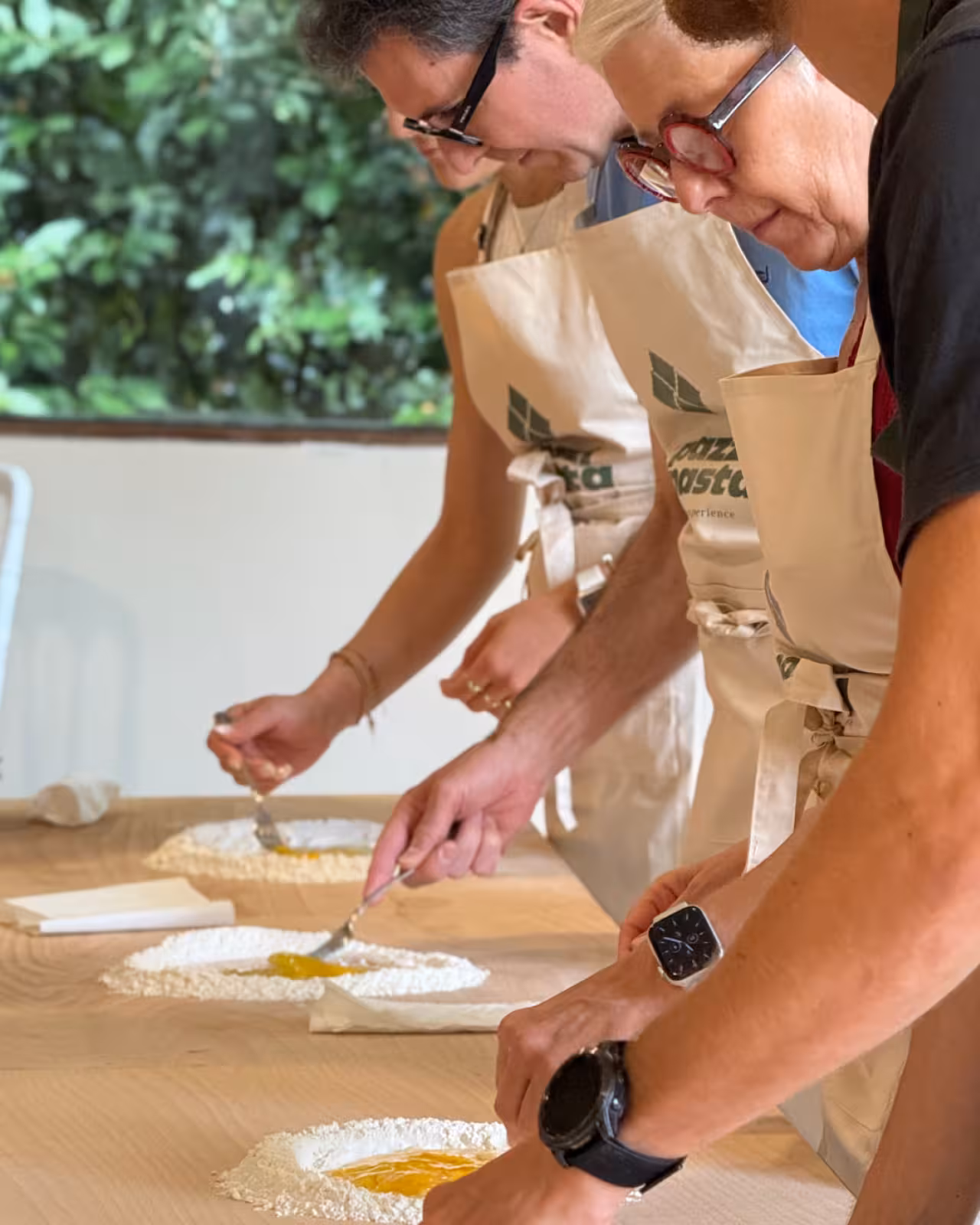 Guests mix eggs into flour wells during a Marche handmade pasta class, preparing fresh dough at a wooden table