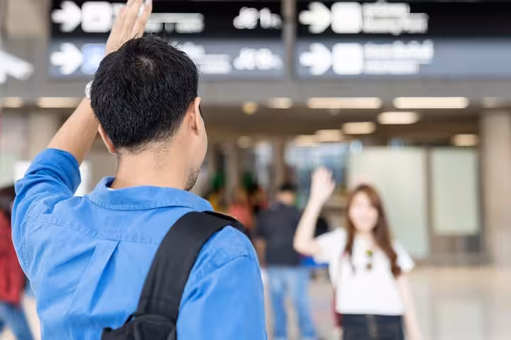 Travelers waving goodbye at airport terminal, capturing the ease of Marco Polo Airport's private transfer service to Venice.