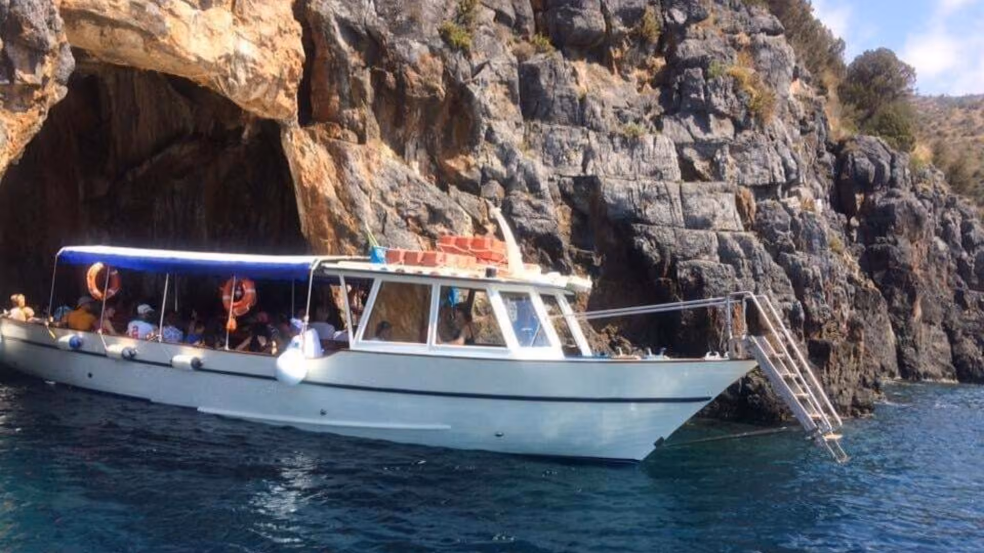 Tour boat navigating past rocky cliffs and caves in Baia Infreschi, popular for Marina di Camerota boat tours.