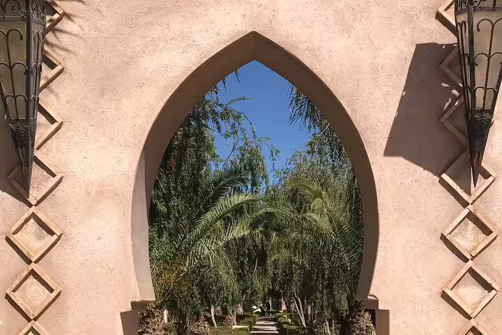 Arched gateway framing palm-lined path in Marrakech medina gardens on Mysteries of the Old City tour
