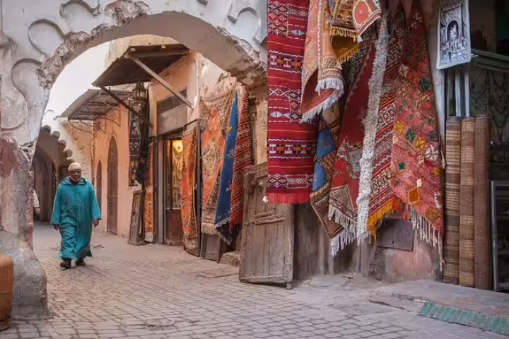 Marrakech medina souk alley with colorful Berber rugs and archway, Morocco 11 days tour from Marrakech