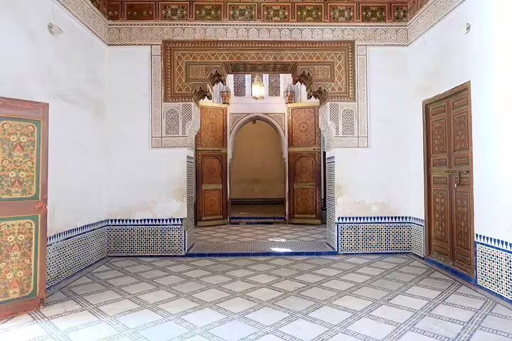 Traditional Marrakech riad interior with zellige tiles and carved cedar doors on a half-day guided sightseeing tour