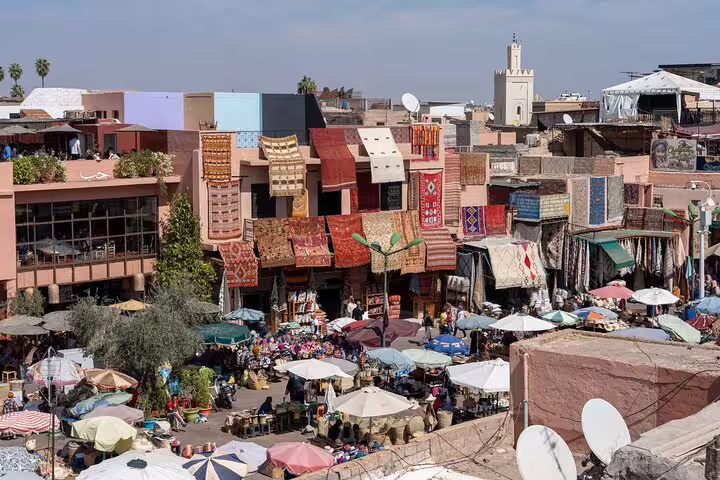 Marrakech souk rooftops with colorful rugs and busy market stalls, featured on Morocco 12 days tour from Casablanca