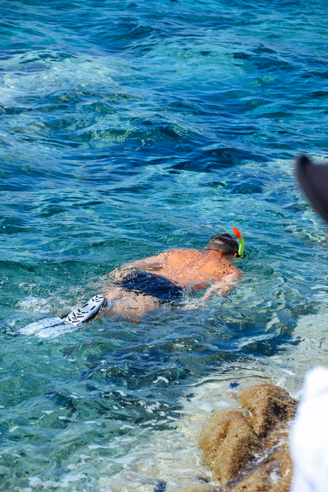 Snorkeler with fins and yellow snorkel exploring crystal clear turquoise waters in Marsa Alam