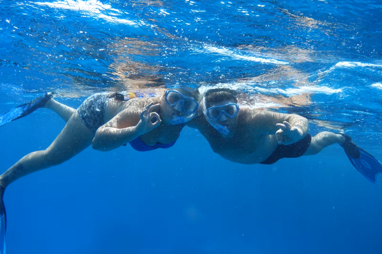 Two snorkelers giving OK sign underwater during Marsa Alam boat tour in clear blue sea
