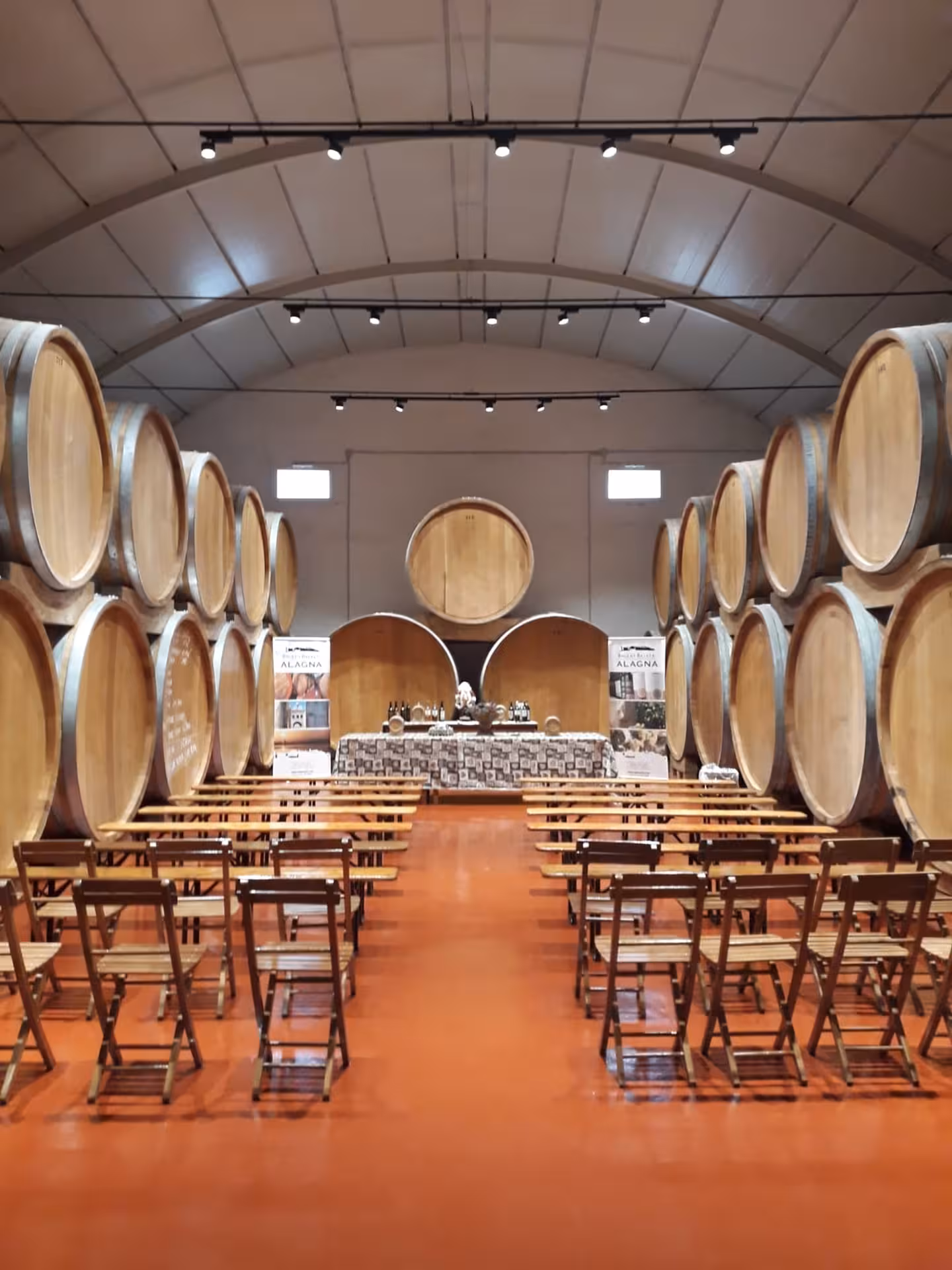 Marsala winery cellar set for tasting, with giant oak barrels and seating for 7-wine and Sicilian dishes tour