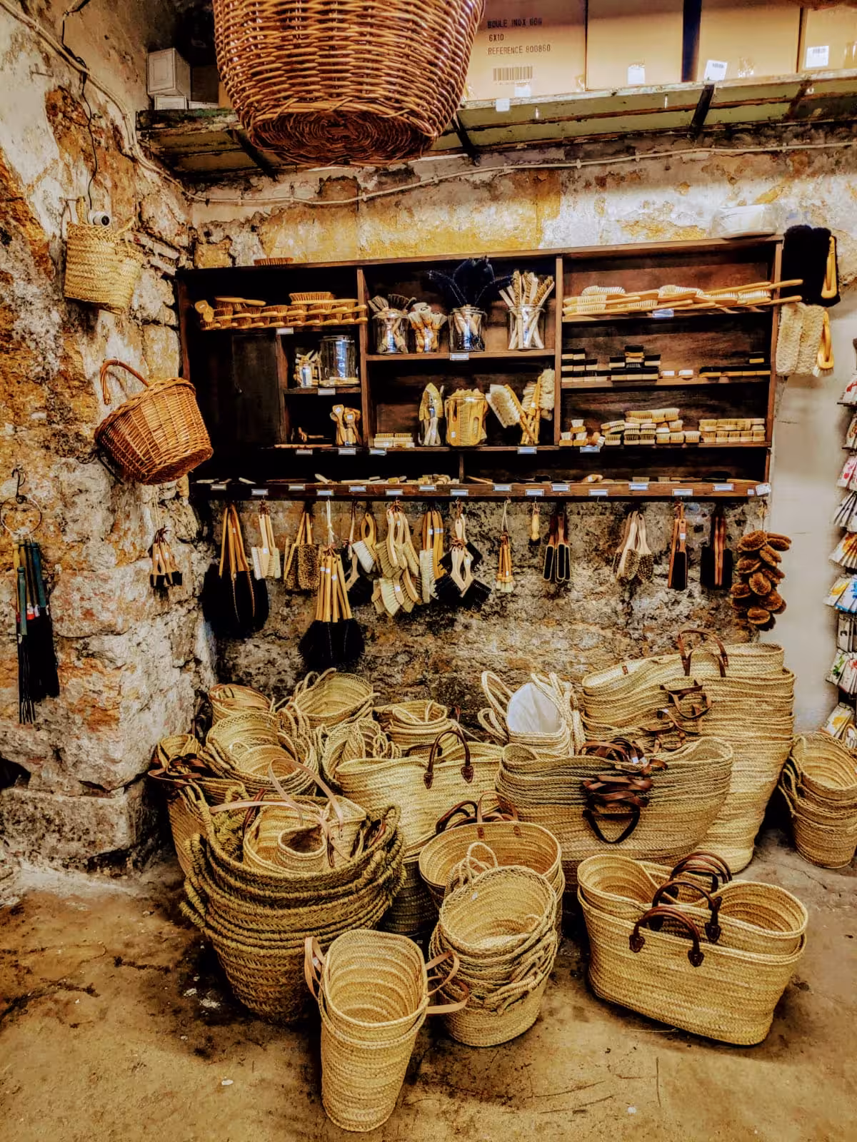 Handmade woven baskets and natural brushes in a rustic Marseille artisan shop, local craft tour stop