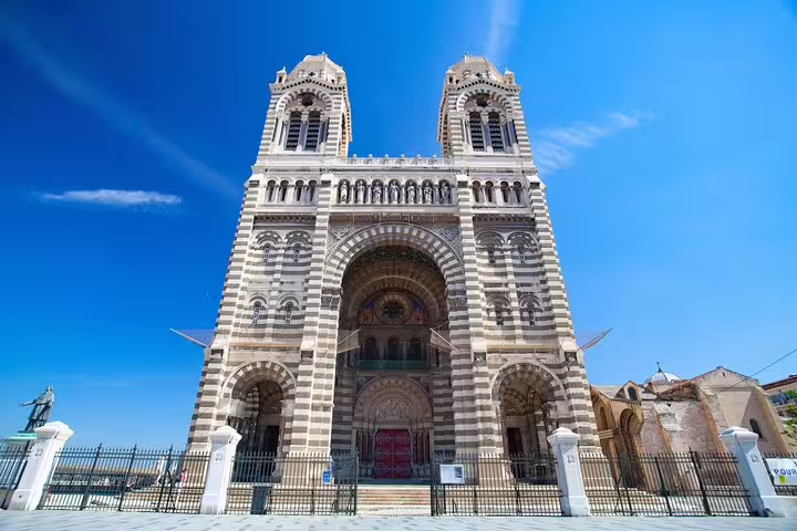 Marseille Cathedral facade with striped stone towers and arched entrance under blue sky