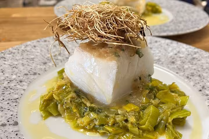 Local chef cooking workshop in Marseille showcasing cod on braised leeks with olive oil and crispy garnish