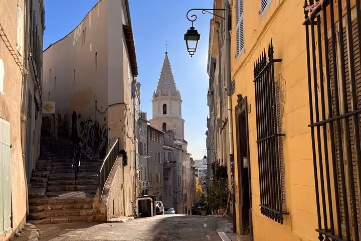Narrow cobblestone street in Le Panier district Marseille with church bell tower and traditional buildings