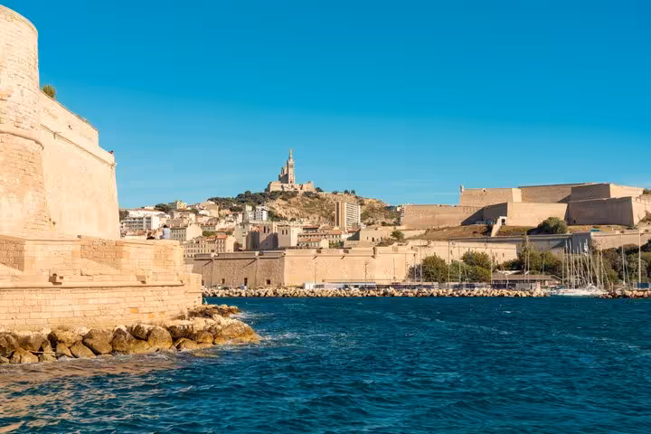 Marseille Old Port waterfront with Fort Saint-Nicolas and Notre-Dame de la Garde basilica on hilltop