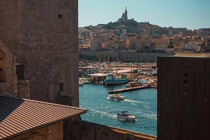 Marseille Old Port with boats, historic fortifications, and Notre-Dame de la Garde basilica on the hill