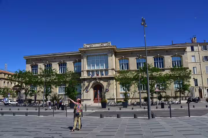 Tourist posing in front of a grand historic building in Marseille Old Town on a sunny day