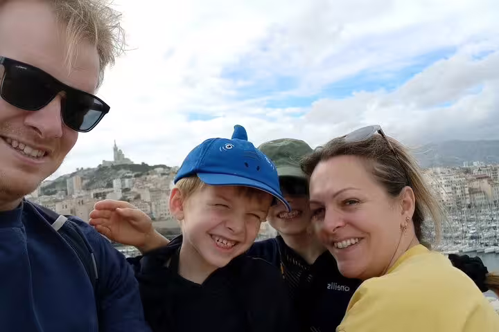 Family selfie with Marseille skyline and Old Port backdrop, enjoying a self-guided scavenger hunt tour