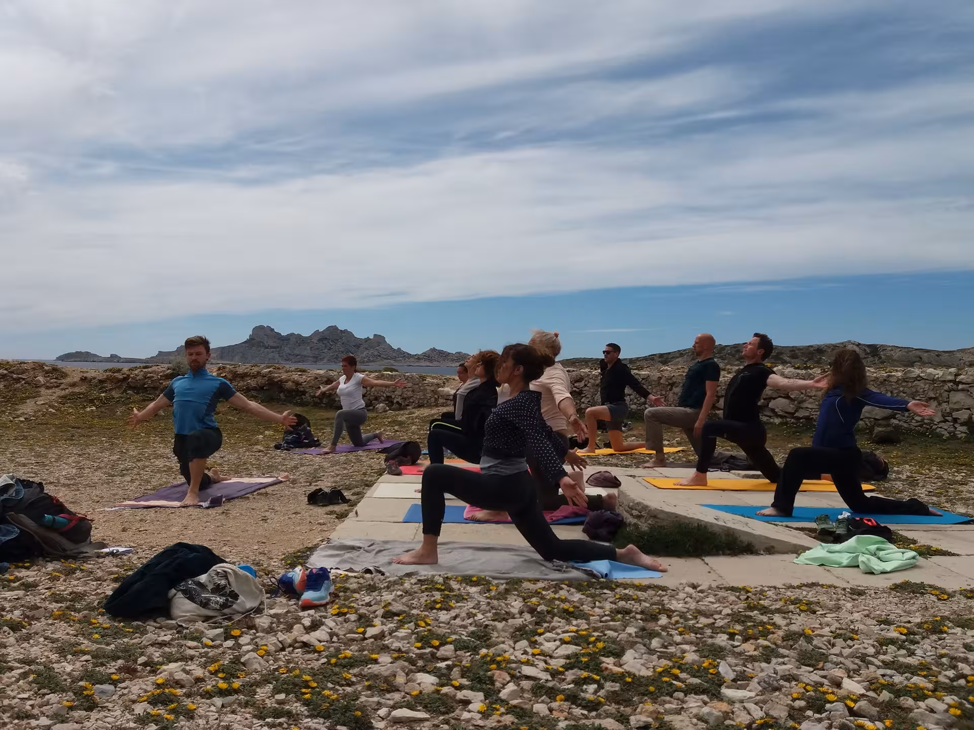Group yoga session on rocky coast near Marseille, sea views and islands, active moment on 3-day tour