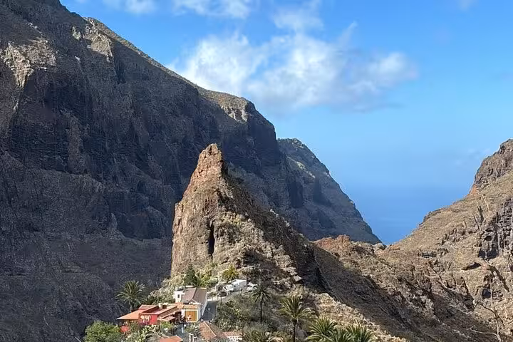 Picturesque Masca village in Tenerife surrounded by dramatic cliffs and vibrant greenery beneath a bright blue sky.