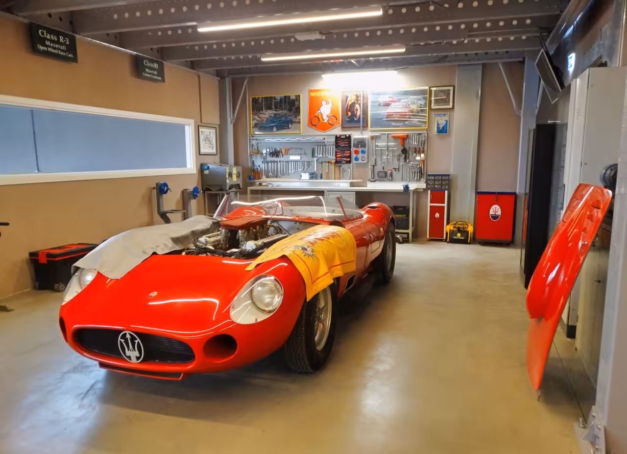 Classic red Maserati race car in workshop display at Umberto Panini Collection Modena museum entrance ticket