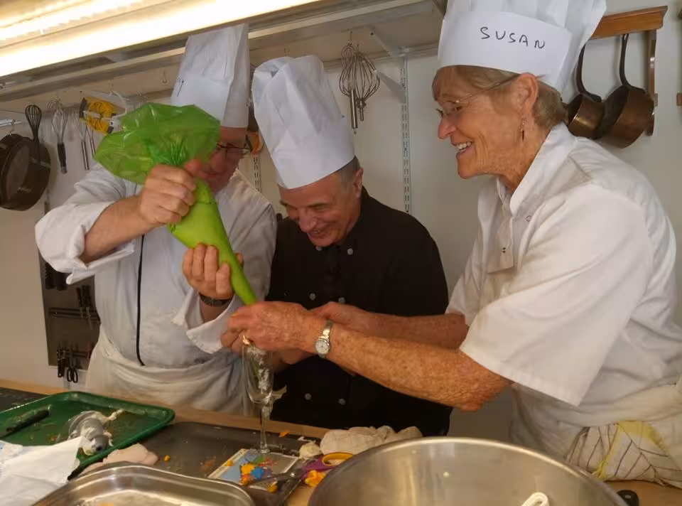 Master chef guiding guests piping filling in a Provence kitchen, hands-on South of France cooking workshop