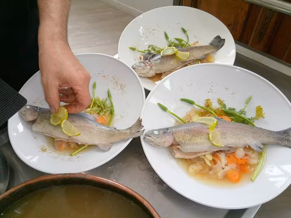 Chef plating Provençal trout with lemon and herbs during a master chef cooking workshop in South of France