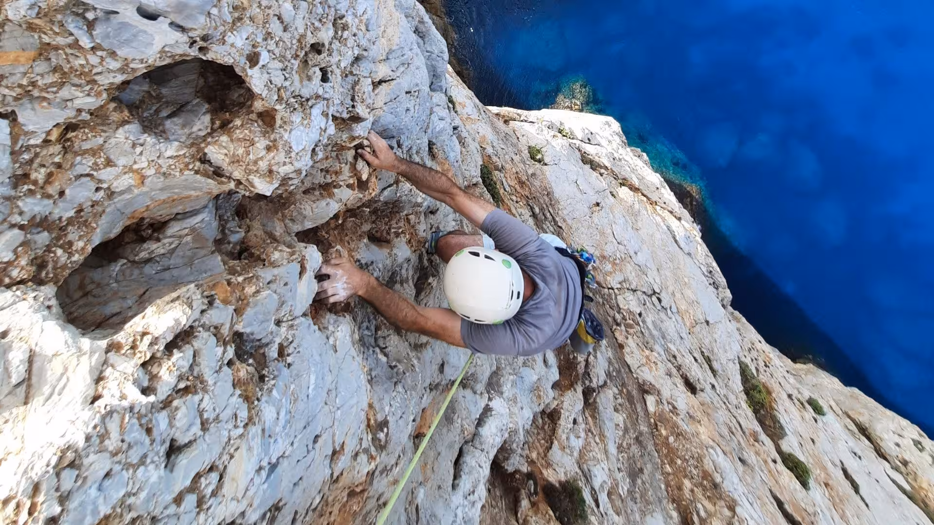 Adventurous climber on rugged cliff with stunning ocean view at Pan di Zucchero, Masua.