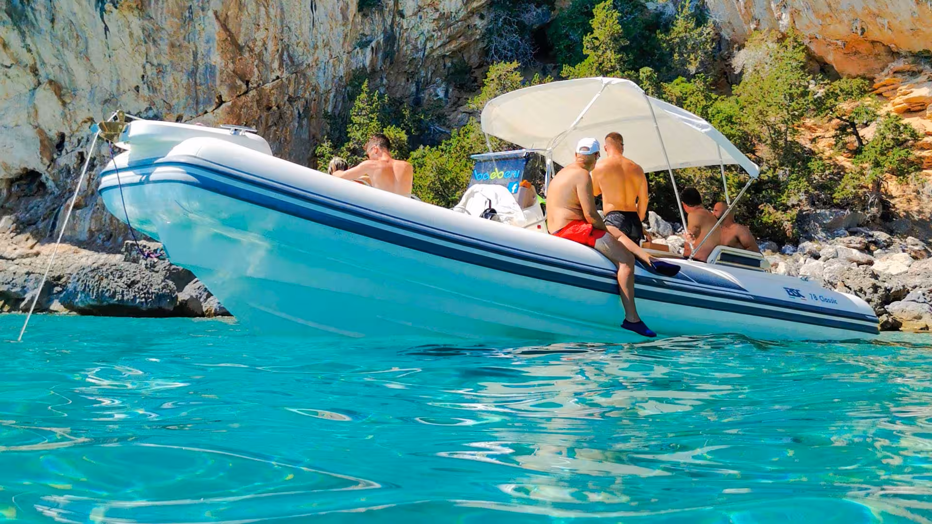 Group enjoying a Maxi dinghy ride in the Gulf of Orosei, surrounded by stunning cliffs and crystal-clear waters.