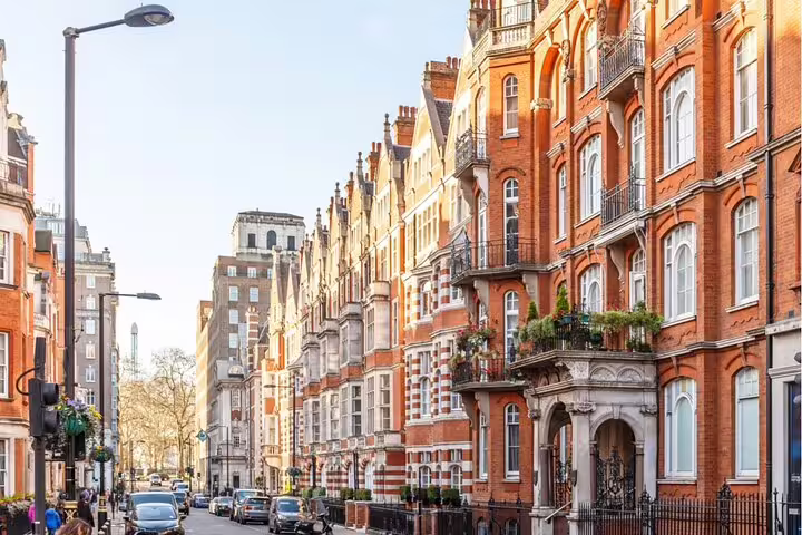 Elegant red brick Victorian mansion buildings lining a sunny Mayfair street in London