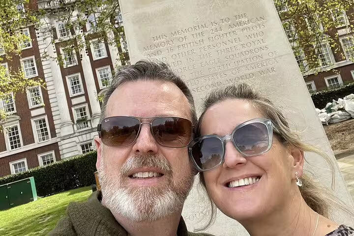 Couple smiling at Eagle Squadron WWII memorial monument in Mayfair, London