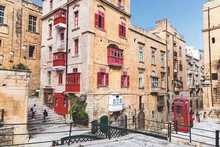 Historic building with red balconies in Mdina, Malta, showcasing classic architecture and a picturesque street scene.