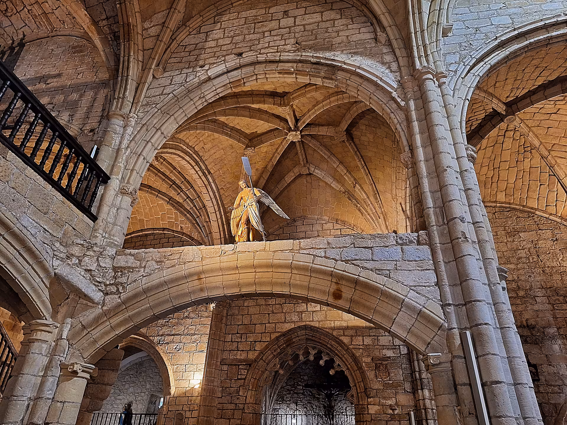 Gothic arches and historic statue inside a medieval church in San Vicente de la Barquera, Spain.