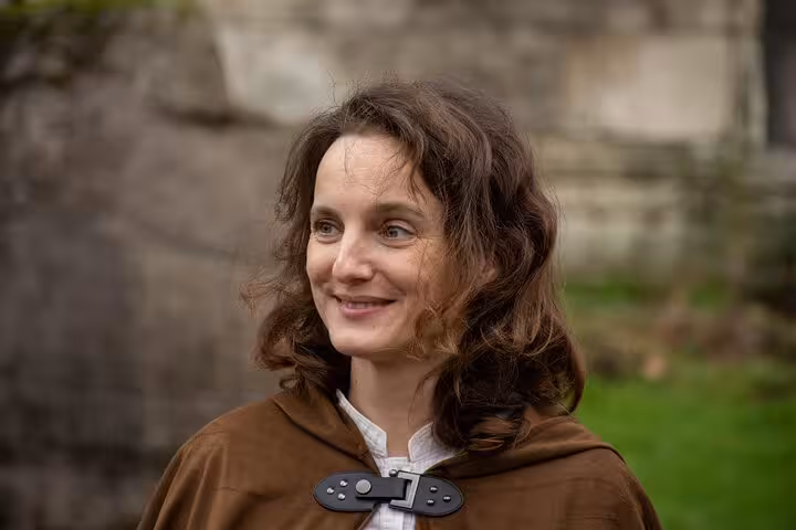 Woman in medieval brown cloak with leather clasp on Joan of Arc walking tour in Rouen