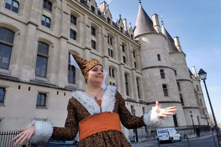 Tour guide in medieval costume standing before Conciergerie castle on Île de la Cité, Paris