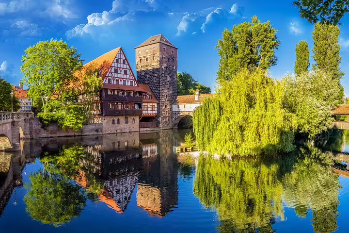 Medieval half-timbered Weinstadel building and Henkersteg tower reflected in Pegnitz River, Nuremberg