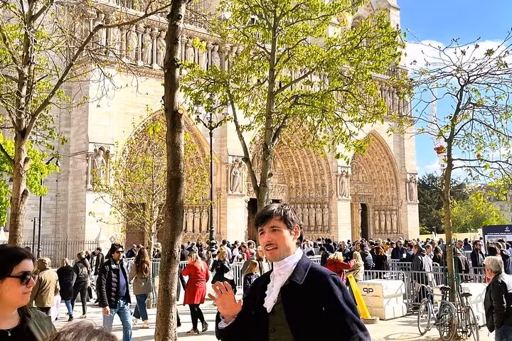 Tour guide in period costume speaking outside Notre Dame Cathedral with crowd of visitors in Paris