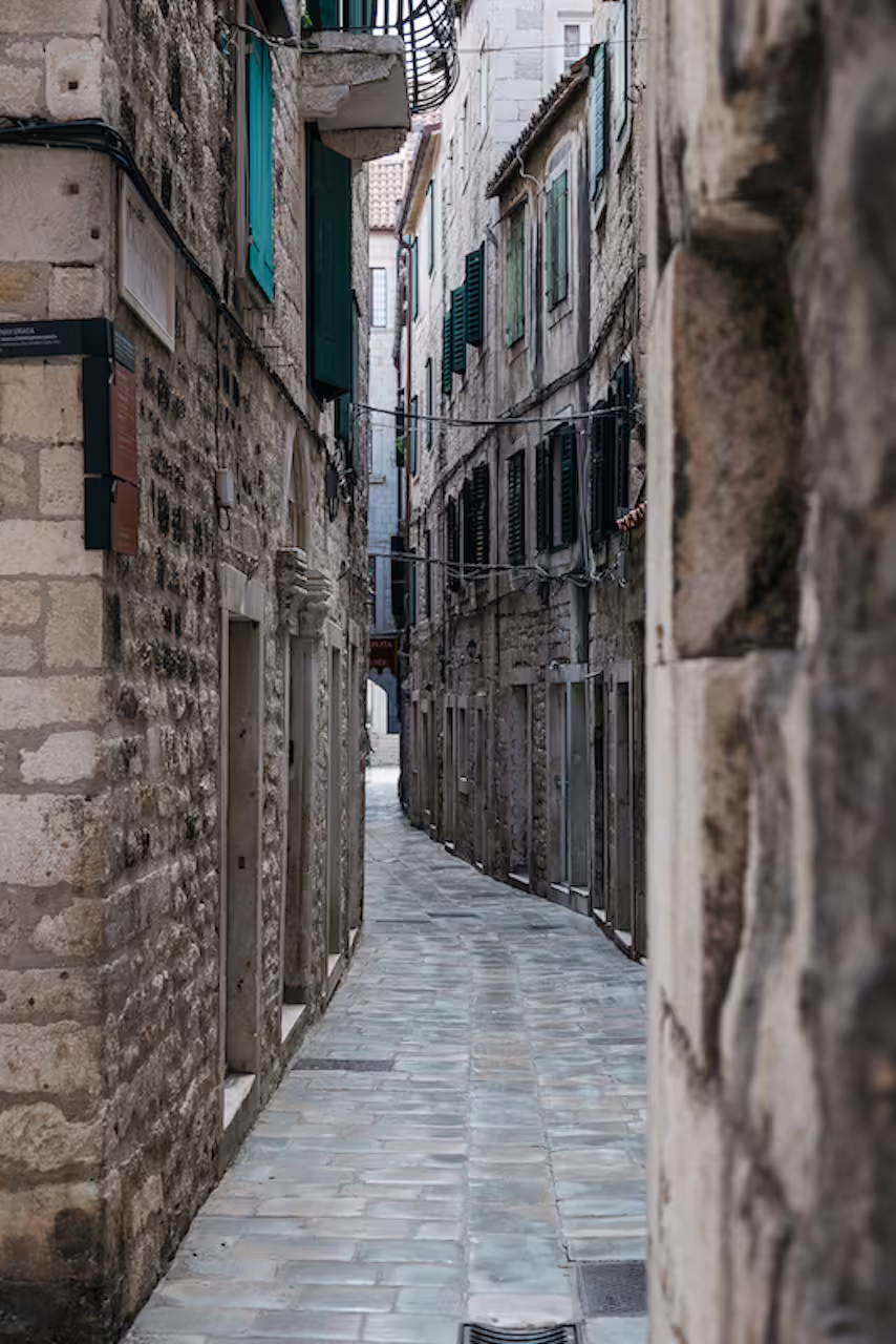 Quiet medieval stone alley with shuttered windows, ideal route on a private walking tour with a local guide