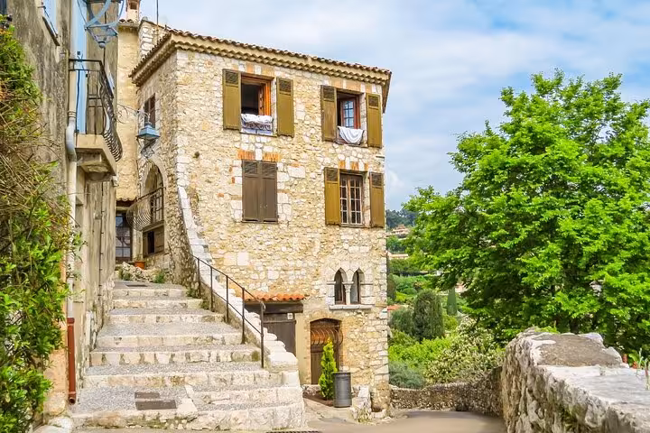 Medieval stone house with wooden shutters and exterior staircase in a Provence village