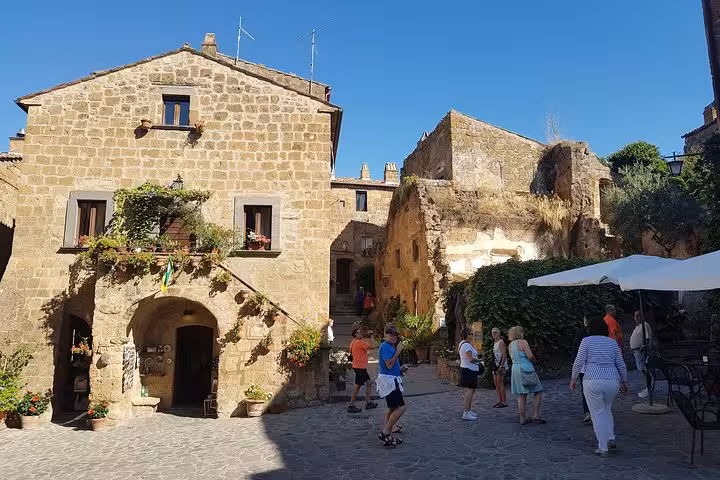 Stone piazza in a medieval Tuscan hill town with travelers, part of 8-day private tour in Italy