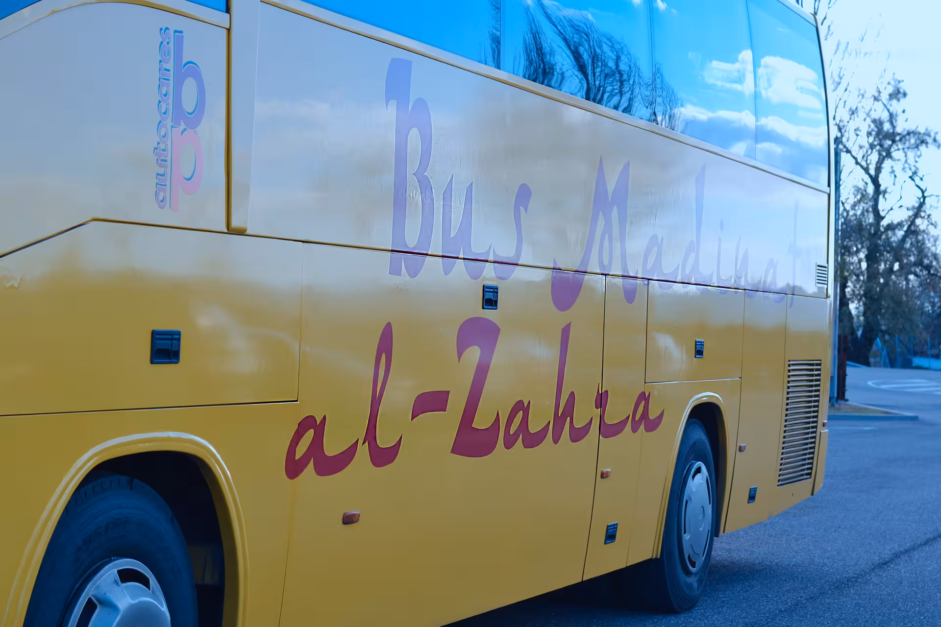 Yellow tour bus labeled 'Bus Medina al-Zahra' ready for a night tour of Medina Azahara.