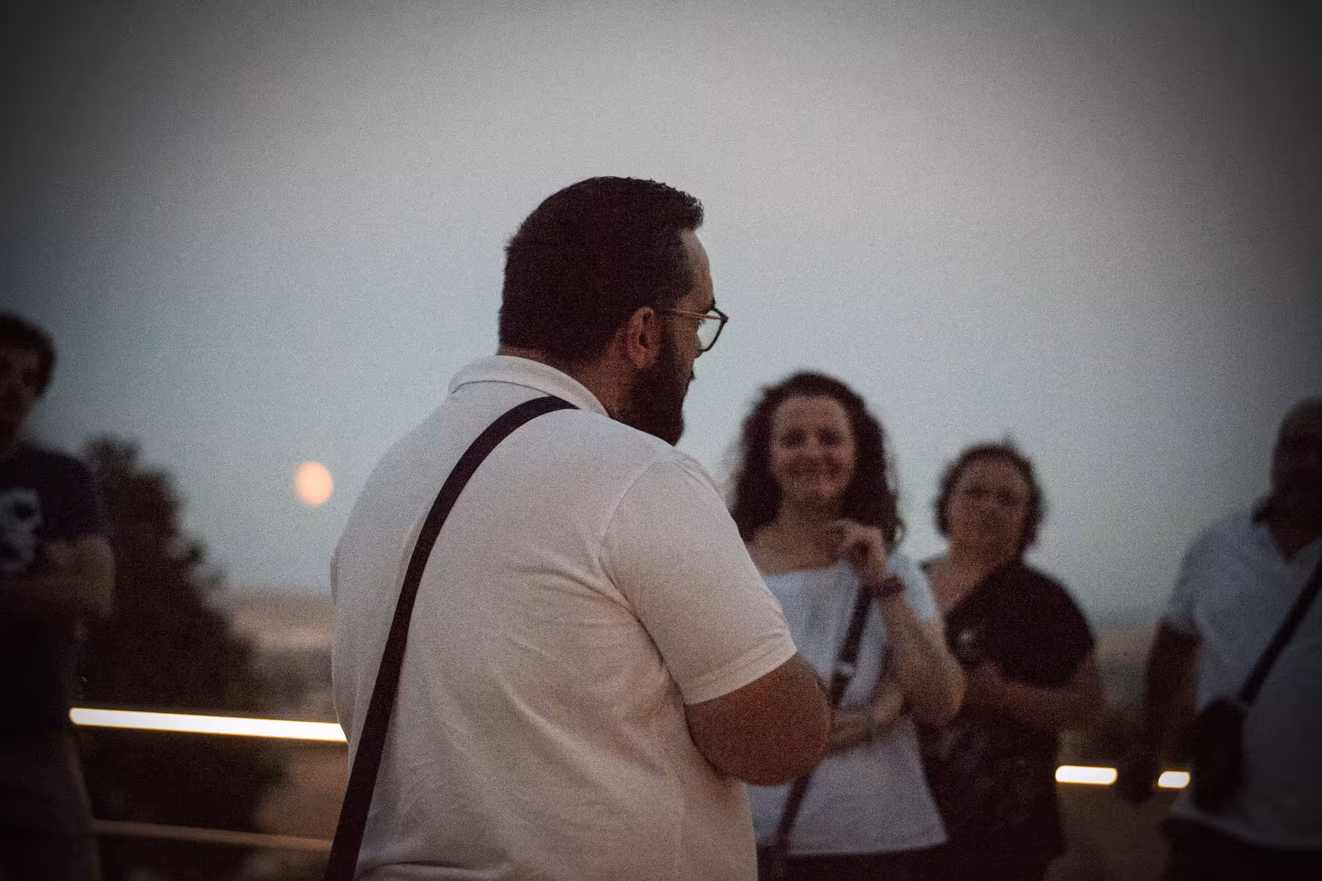 Tour group listens to a guide at dusk during the captivating Medina Azahara night tour experience.